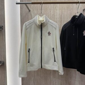 White or cream fleece zip-up jacket with quilted shoulder panels, a stand collar, and a tricolor embroidered logo patch, displayed on a retail hanger.