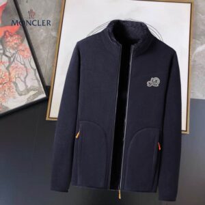 Men's navy blue high-pile fleece zip-up jacket with full faux fur lining, an embroidered logo patch, a stand collar, and contrast-colored zipper pulls.