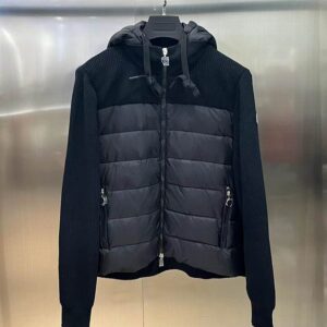 A black hooded hybrid jacket displayed on a hanger, featuring a horizontally quilted puffer panel on the front torso and black ribbed knit material on the sleeves and back. A small logo patch is visible on the left arm.