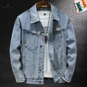 Image of a light blue/light wash denim jacket with button closures, a collar, and two chest pockets with diagonal silver zippers, worn by a model over a white shirt. A stitched logo patch is on the left chest.