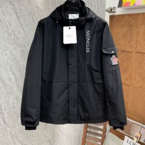 Image of a black technical utility-style jacket with a hood, a vertical white logo running down the right chest, front snap pockets, and a patch pocket with a logo emblem on the left sleeve.