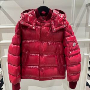 A vibrant high-shine red puffer jacket with horizontal quilting, featuring a detachable hood and a snap-button pocket on the left sleeve with a logo.