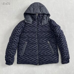 Dark navy and gray monogram puffer jacket with an attached hood lying flat on a tiled floor, showcasing the all-over logo pattern.
