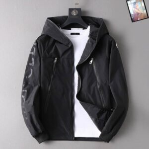 Black Moncler hooded windbreaker jacket on a hanger, featuring large, tonal black logo lettering down the left sleeve. Styled over a white t-shirt.