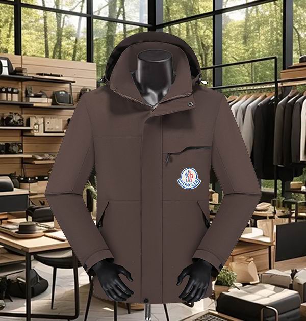 Brown men's Moncler-style waterproof jacket displayed on a mannequin, featuring a concealed hood, an angled chest pocket zipper, and a round, multicolored Moncler-style logo patch on the chest