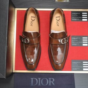 A pair of Polished Cognac Brown Leather Dior Inspired Loafers featuring a silver buckle on a red display stand.