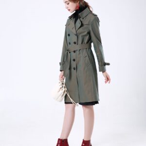 A midi-length, double-breasted trench coat in a polyester-cotton blend featuring a belted waist with leather buckle, shoulder epaulets, and a structured turn-down collar.