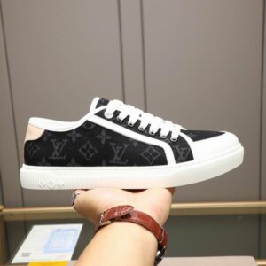 Close-up of a Monogram Black and White Low Top Canvas Sneaker with white laces and a thick white sole held by a hand.