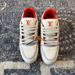 Profile view of Louis Vuitton LV Trainer in white grained leather with red piping and script signature on the side