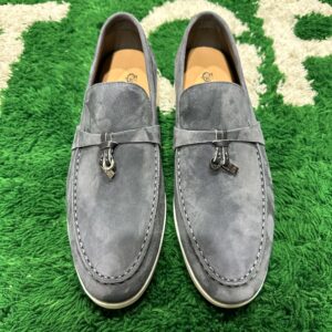Pair of slate-grey suede slip-on loafers with white rubber soles and silver metal strap charms.