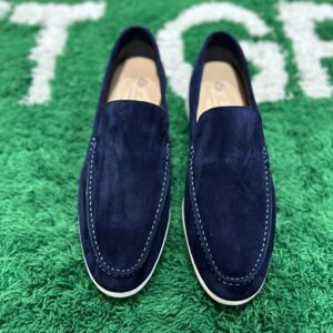 Pair of Loro Piana Summer Walk loafers in navy blue suede with white rubber soles on a green textured surface.