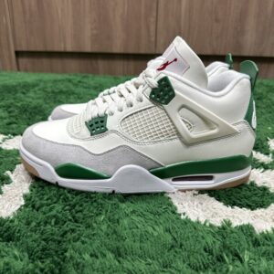 A side-profile view of the Air Jordan 4 x Nike SB 'Pine Green' Sneakers resting on a green rug, featuring Sail leather, grey suede, and pine green accents.
