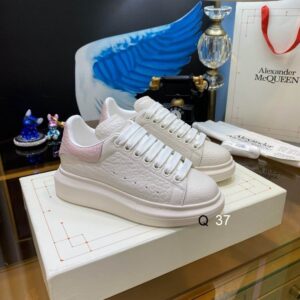Side view of Alexander McQueen White and Pink Croc-Embossed Oversized Sneakers featuring textured white leather and a soft pink heel tab.