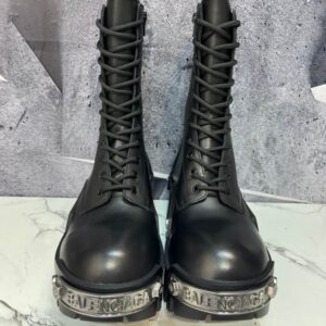 Front view of Balenciaga Hummer black leather tall boots with prominent silver logo metal plates on the toes.