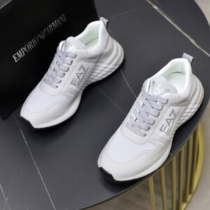 A pair of EA7 Emporio Armani White Silver Runner Sneakers on a black marble surface featuring silver branding and wave-textured heels.