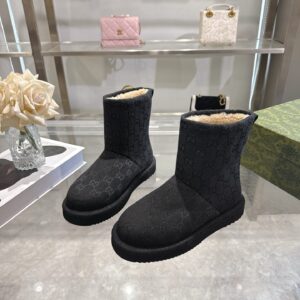 A pair of Gucci Black Monogram Winter Boots with cream shearling lining and a ridged black sole.