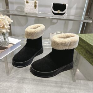 A pair of Gucci Black Shearling Ankle Boots with black suede and cream fur trim.