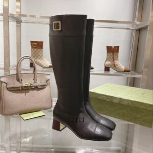 Pair of black leather knee-high boots displayed with a designer handbag, showing the perforated toe cap detail.