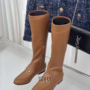 Profile shot of brown leather knee-high boots with gold horsebit hardware against a fashion background.