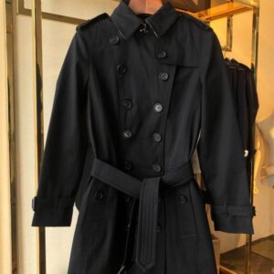Mid-length double-breasted unisex trench coat in Black with belted waist and classic check lining. Tailored Kensington-style.