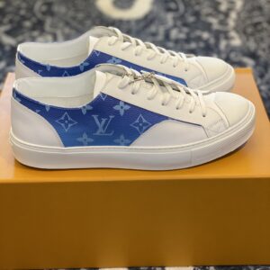 Pair of white luxury low-top sneakers featuring a blue Monogram logo panel on the side, displayed on an orange box