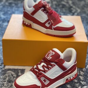 Top-down view of a pair of Louis Vuitton Trainer Sneakers in red and white leather positioned below an orange brand box.