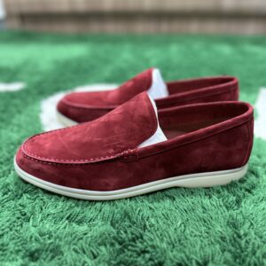 Luxury burgundy suede Loro Piana Summer Walk loafers with white rubber soles shown with original packaging and accessories on a green surface.