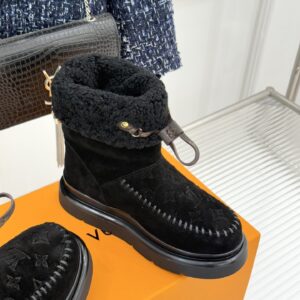 A pair of Louis Vuitton Black Suede Monogram Boots in black suede with embossed patterns and black fur trim.