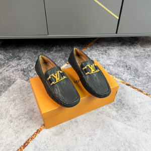 A pair of Louis Vuitton Black Textured Logo Loafers featuring vertical-wave leather and a gold-tone buckle on an orange box.