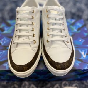 The Louis Vuitton Frontrow Sneaker in white debossed monogram leather with gold-tone eyelets and a clean white rubber sole.