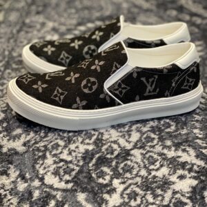 A top-down and side view of the Louis Vuitton Slip-On Sneaker in black denim monogram featuring white trim and a white rubber midsole.