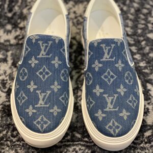 A pair of Louis Vuitton Slip-On Sneakers in blue monogram denim showing the woven pattern, white leather trim, and white rubber midsole.