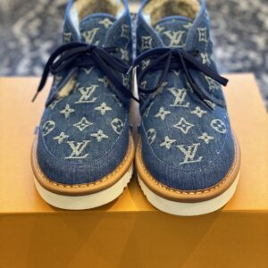 Front view of the Louis Vuitton Snowdrop Flat Ankle Boot in blue monogram denim with visible shearling lining and a white serrated sole.