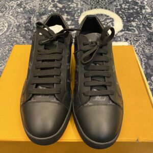 Pair of all-black low-top leather trainers with tonal Louis Vuitton-style monogramming on the sides and a smooth black toe cap.