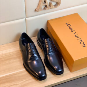 Louis Vuitton Symmetrical Wingtip Black Shoes featuring smooth black leather and unique curved wingtip seams on a wooden display.