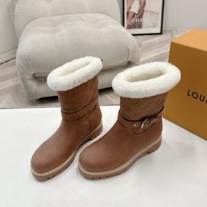 A pair of Louis Vuitton Tan Monogram Embossed Boots in tan leather with white fur trim and a buckled strap.