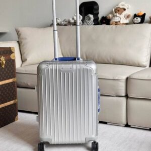 view of the Rimowa Silver Blue Suitcase in metallic blue and silver with grooved aluminum texture and four spinner wheels.