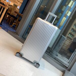 A tall Rimowa Silver Trunk Plus Luggage in sleek silver aluminum with a telescopic handle and multi-wheels.
