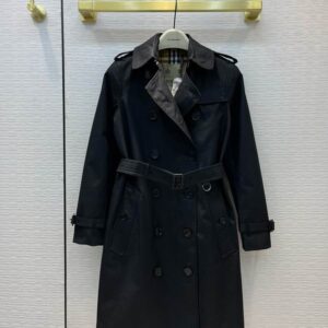 Short navy blue double-breasted trench coat for women with a self-tie belt, matte dark buttons, and sharp collar details, styled on a model.