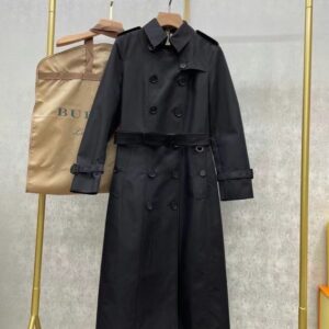 Long double-breasted unisex trench coat in black with a belted waist and classic check lining. Westminster-style coat.