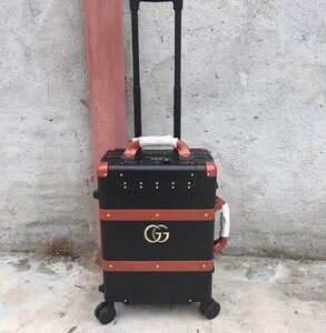 Side view of Gucci Black and Brown Rolling Suitcase showing brown leather-style straps and gold studs.