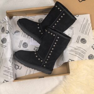 : A pair of UGG Black Studded Shoes Boots in black suede with silver studs inside an UGG box.