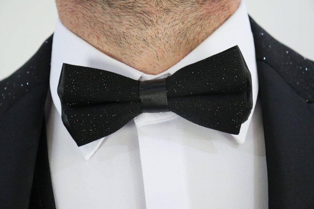 https://suitbae.com/cdn/shop/files/black-sparkly-tuxedo-matching-bow-tie-with-white-hidden-button-suitbae-cufflink-shirt-close-up.jpg?v=1734026015&width=1946
