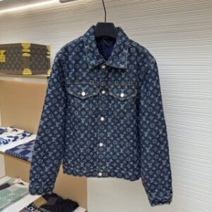Premium dark blue Louis Vuitton Monogram Denim Jacket featuring the iconic LV monogram pattern throughout. Classic trucker-style denim jacket with branded silver buttons hanging in a high-end boutique display.