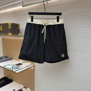 A pair of Moncler Black Swim Shorts with a contrast cream waistband and logo patch hanging in a boutique.