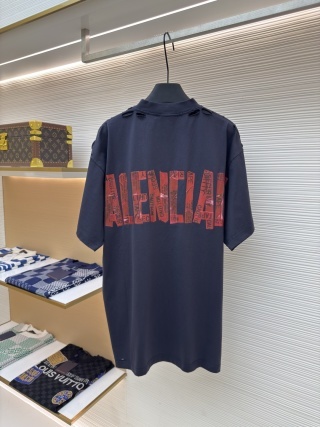 A men's Balenciaga dark navy oversized washed cotton t-shirt with a red tape logo on the back hanging on a clothes rail.