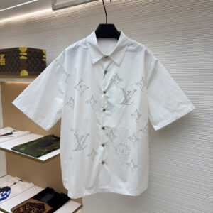 Front and back view of a white Louis Vuitton short-sleeved shirt with perforated monogram patterns hanging in a boutique.