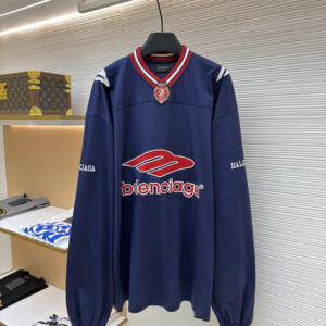 A navy blue long-sleeve athletic jersey with red and white graphics and a striped V-neck hanging in a boutique.