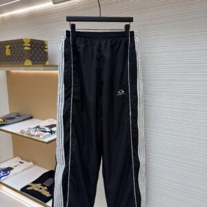 A pair of black Balenciaga oversized track pants with white side stripes hanging in a luxury boutique