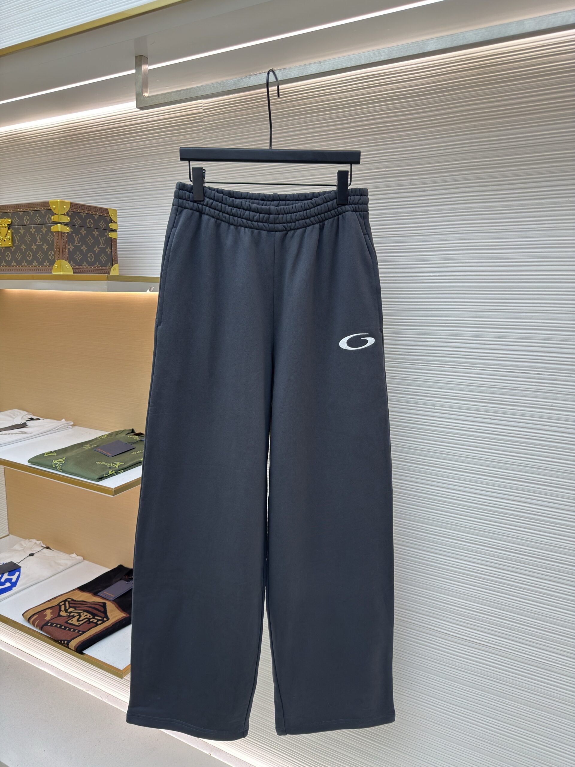 Dark grey wide-leg Balenciaga sweatpants with an elastic waistband and a small white Unity logo on the front left leg.